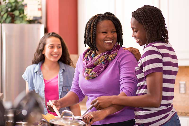 mother and daughter cooking in kitchen smiling