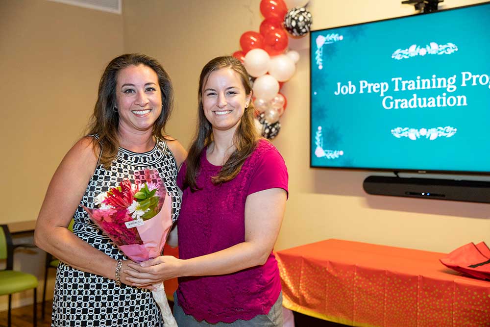 Volunteer, Lelani and Youth Villages staff posing for photo holding flowers at Job Prep event