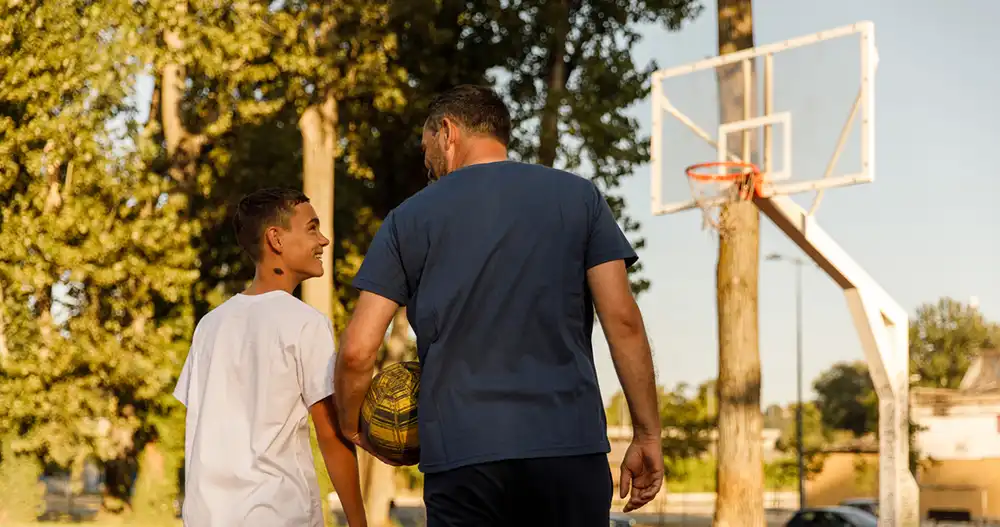 young person and an adult playing basketball