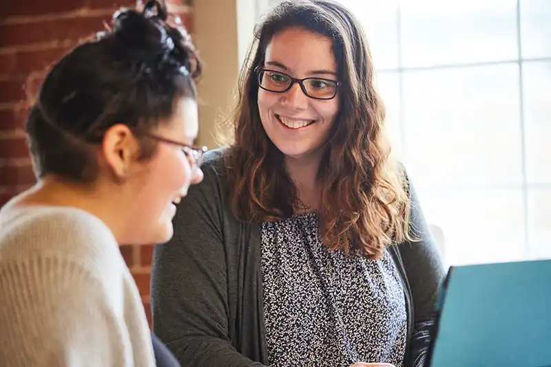 young women with adult smiling at a computer